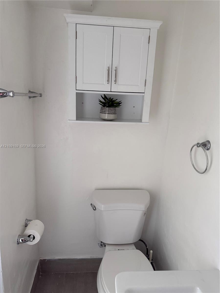 Wall-mounted white cabinetry featuring double doors and an open storage shelf, complemented by chrome hardware including a towel bar and circular ring