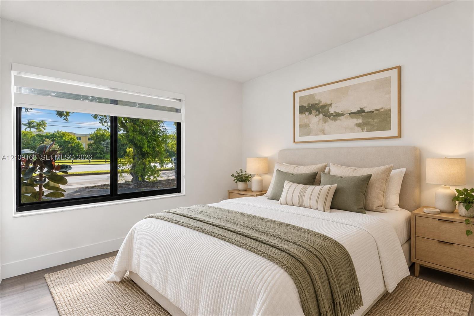 Bedroom featuring large-format window with black framing and light-toned wood-finish flooring