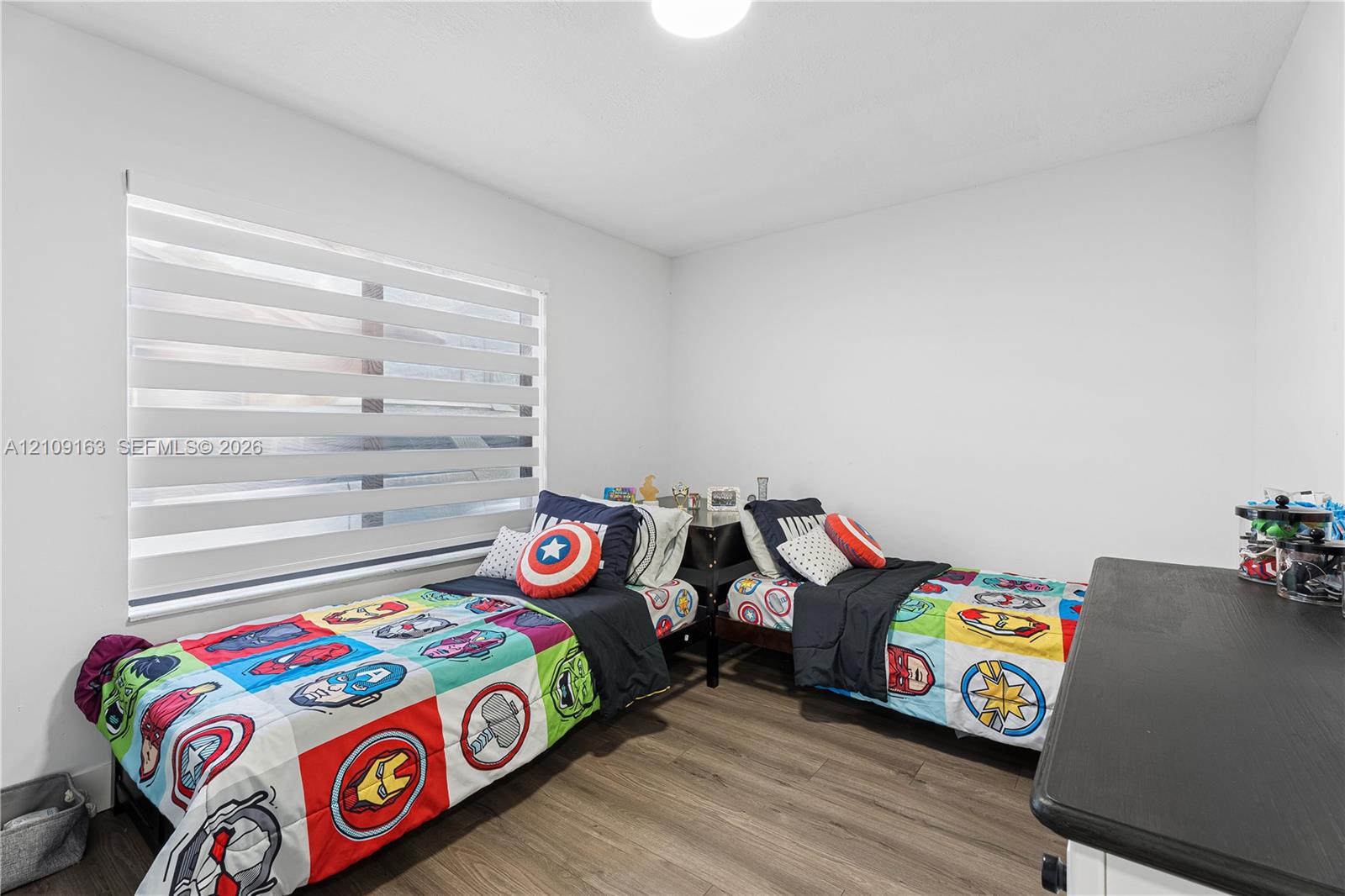 Neutral-toned walls, wood-finish flooring, and horizontal dual-layer light-filtering window shades