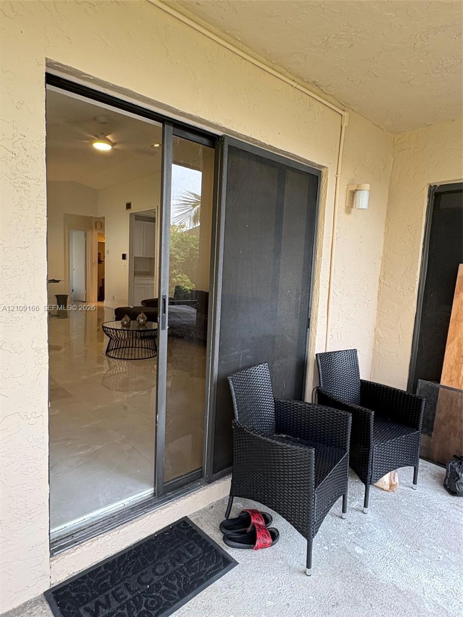 Covered patio featuring a concrete floor, stucco exterior wall, and sliding glass door with a metal screen frame