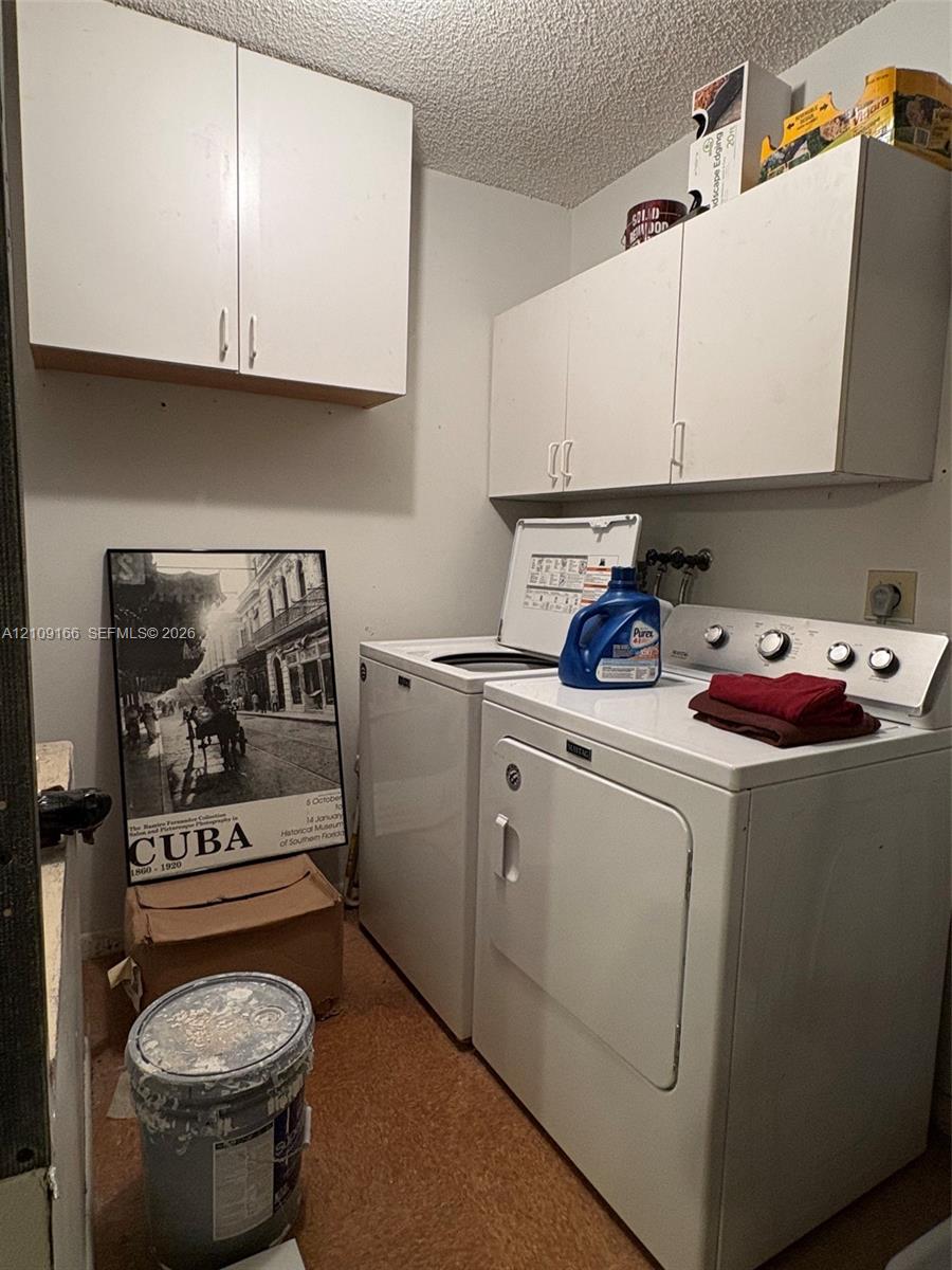 White wall-mounted cabinetry providing overhead storage and solid surface flooring