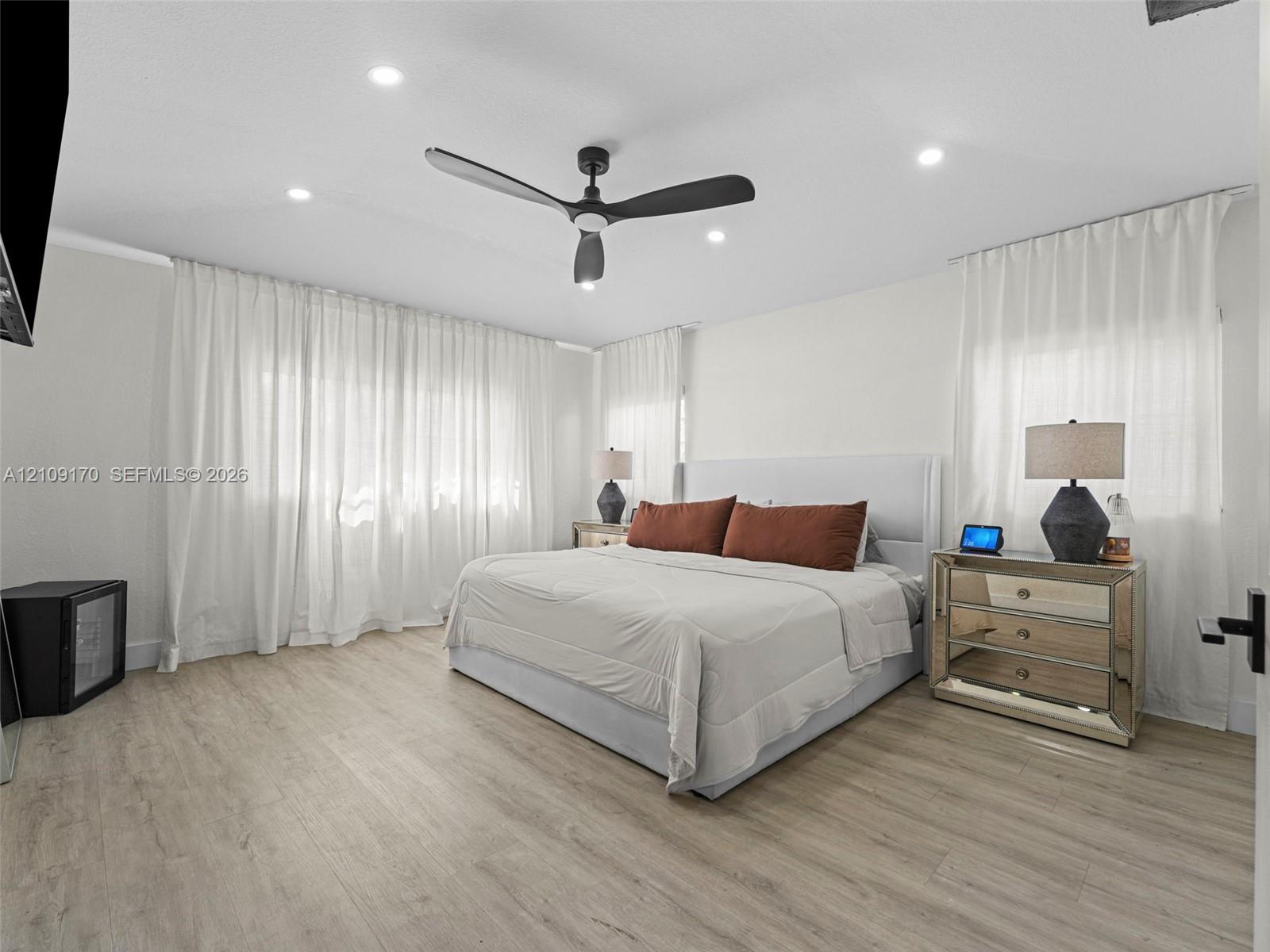 Neutral-toned wood-finish flooring, recessed lighting, and a modern three-blade matte black ceiling fan