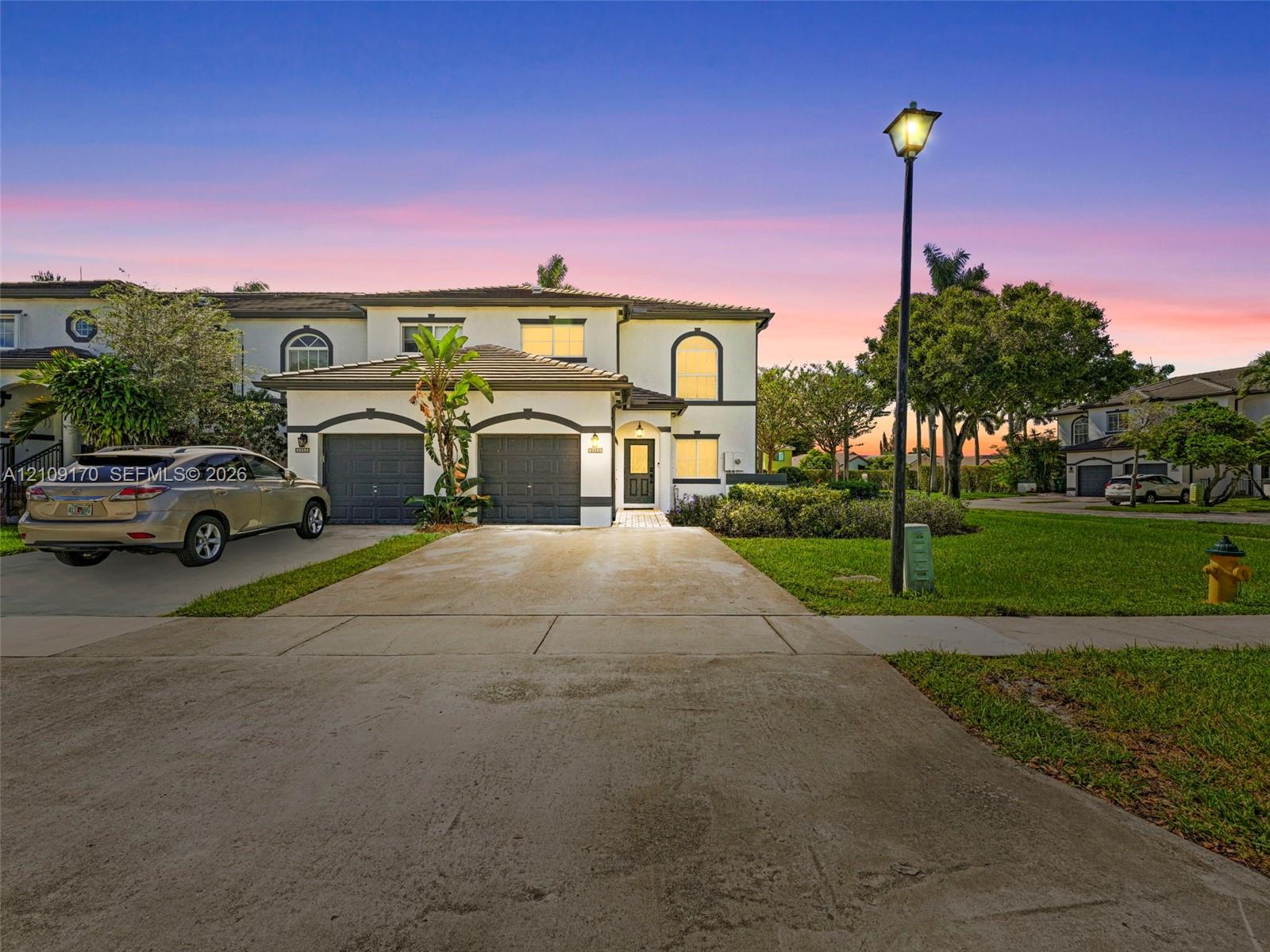 Two-story exterior featuring a stucco facade, concrete tile roof, dual-bay garage, and arched window detailing Two-story exterior featuring a stucco facade, concrete tile roof, dual-bay garage, and arched window detailing