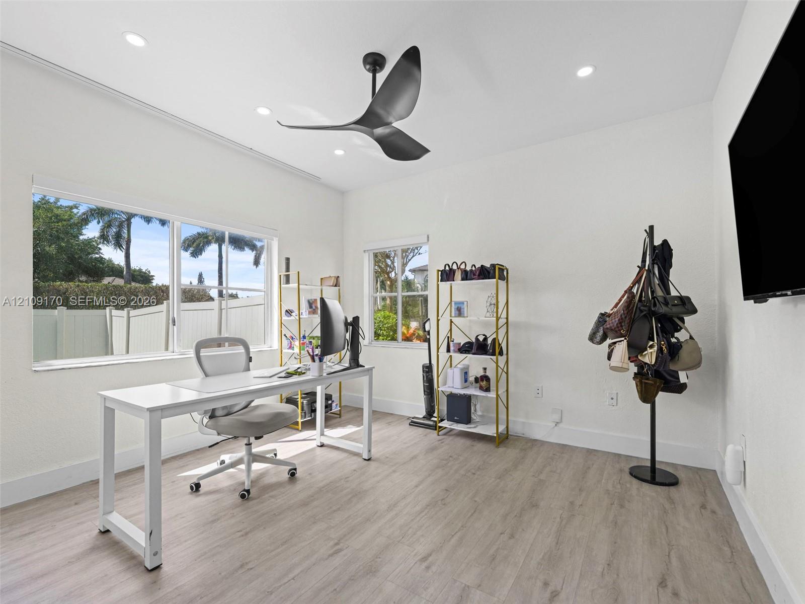 Room featuring wood-finish flooring, recessed lighting, and a multi-blade ceiling fan, with white-frame windows