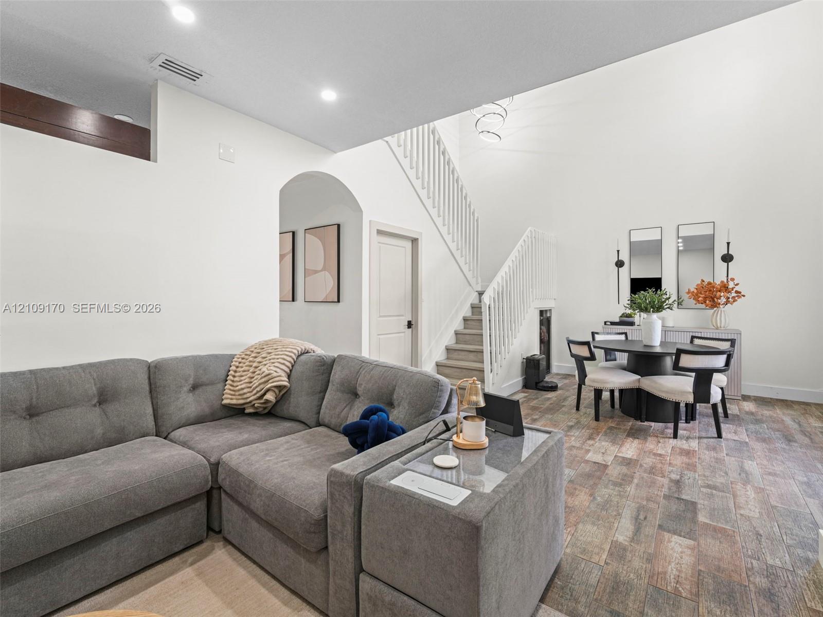 High ceilings, wood-finish flooring, staircase with white railing, and architectural archway High ceilings, wood-finish flooring, staircase with white railing, and architectural archway