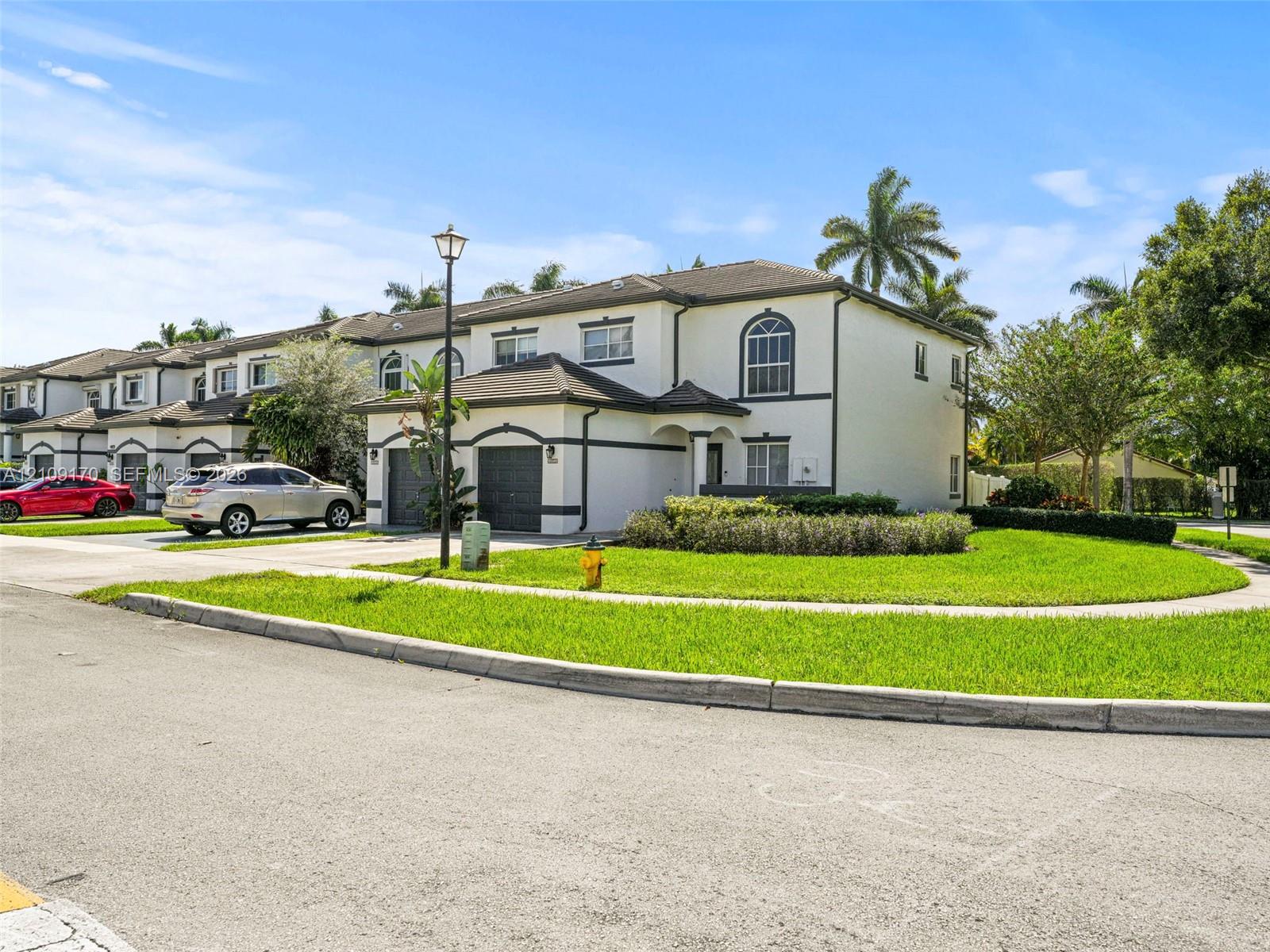 Two-story stucco exterior featuring a hipped tile roof, arched window detailing, and attached garage