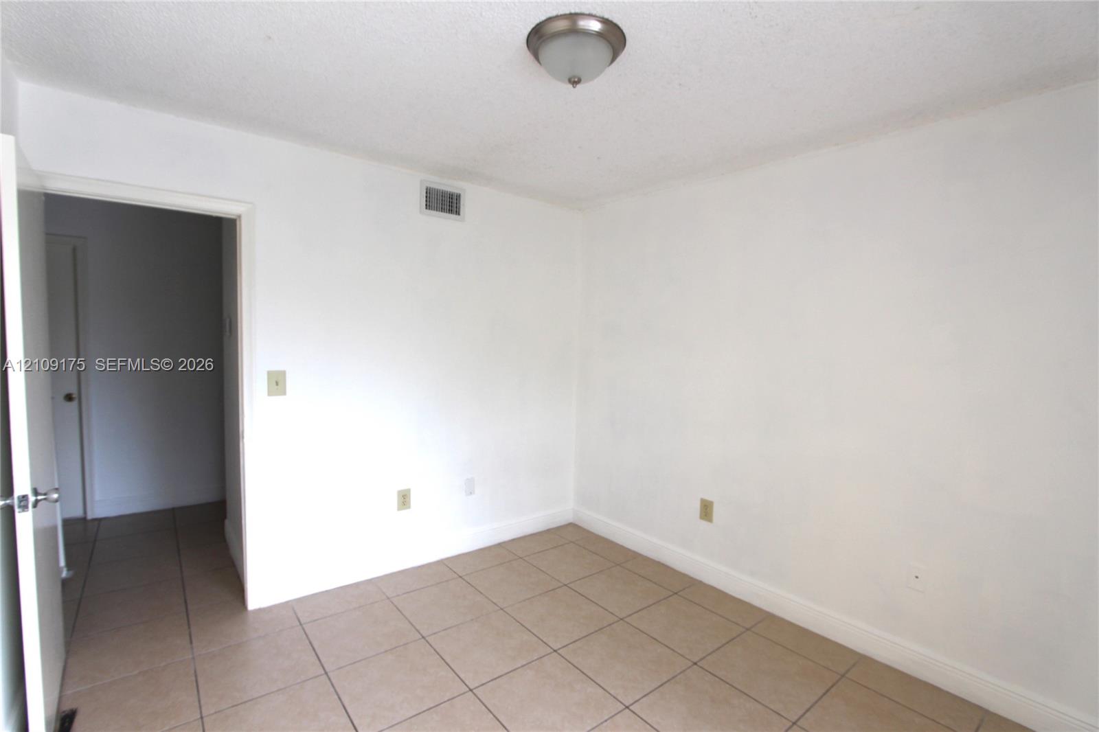Neutral-toned ceramic tile flooring and ceiling-mounted flush light fixture