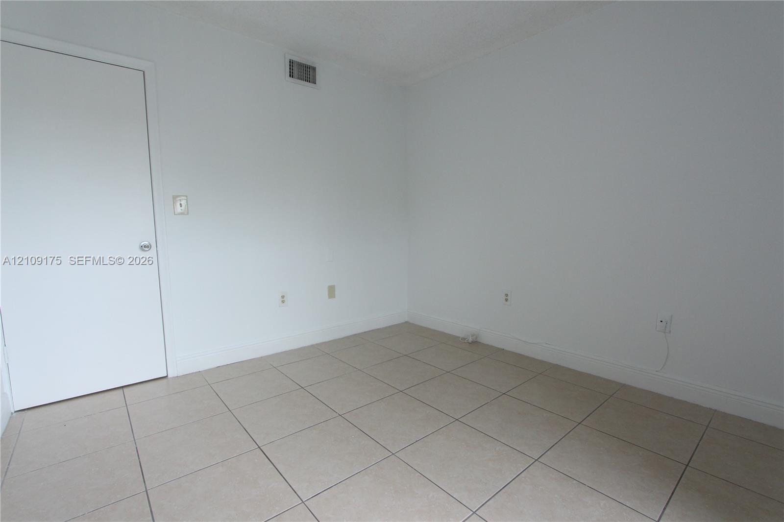 Room featuring neutral wall finishes, large-format tile flooring, and a solid-core interior door