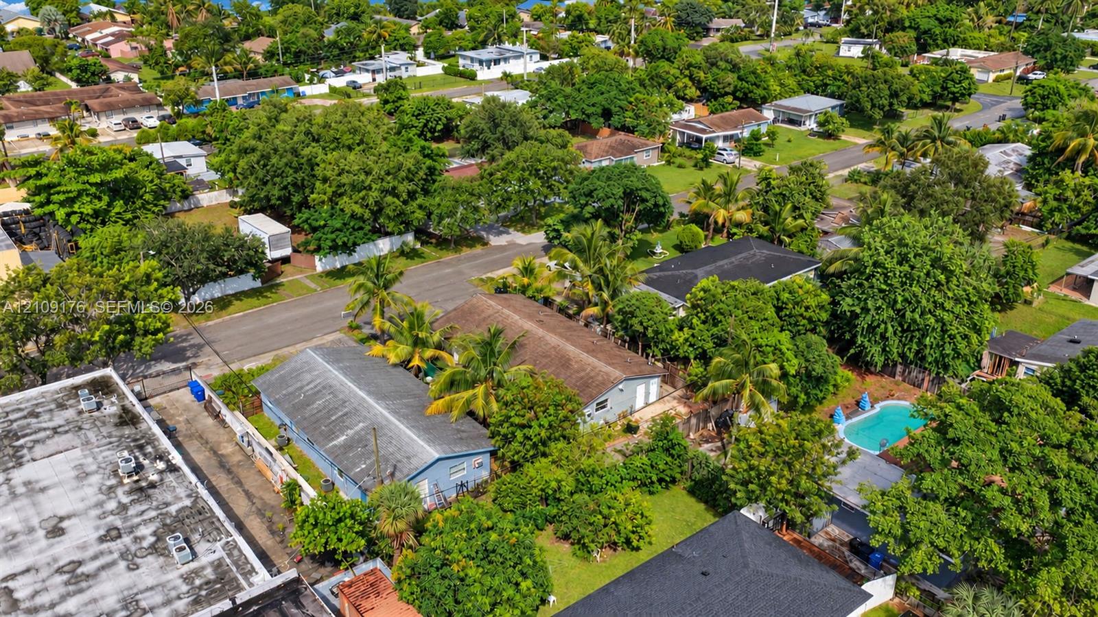 Aerial perspective featuring residential structures, mature tropical trees, and a private swimming pool