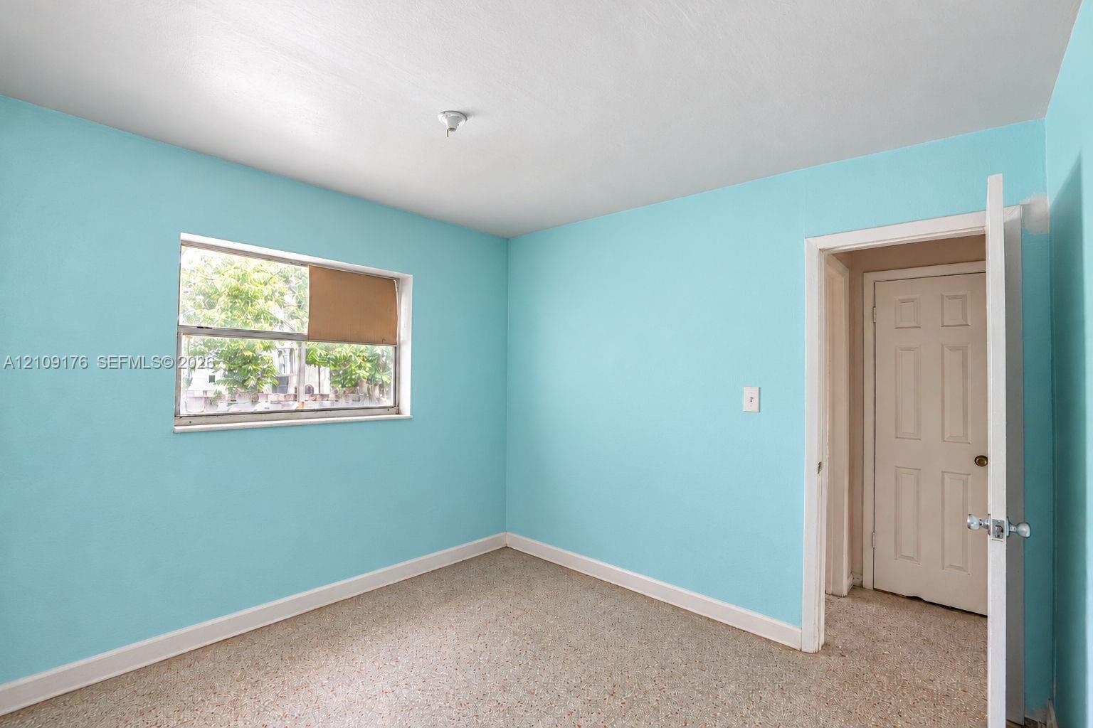 Room featuring a single-pane window, carpeted flooring, and a six-panel interior door