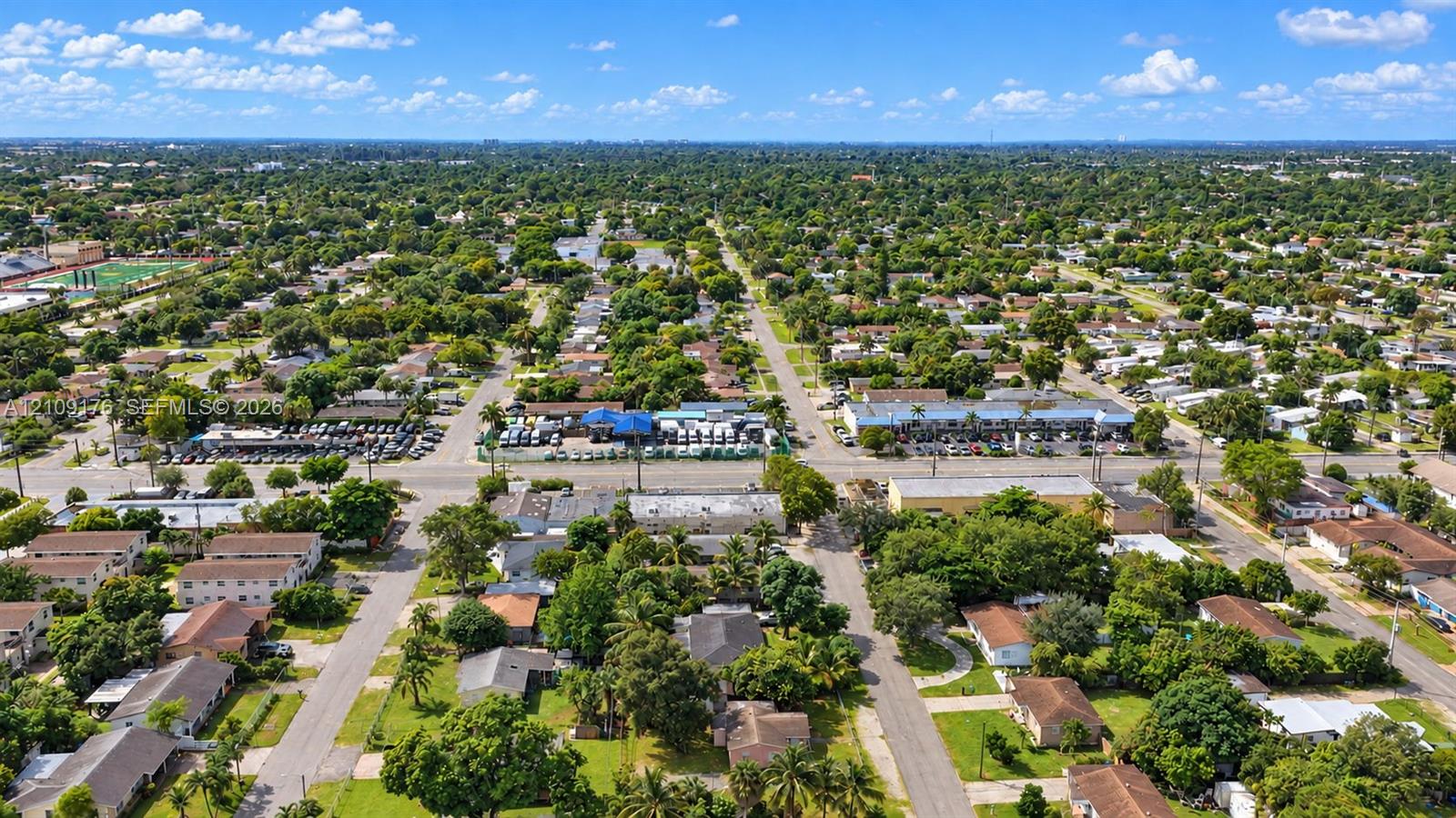 Aerial perspective of a suburban neighborhood featuring tree-lined streets, established residential lots, and proximity to local commercial thoroughfares