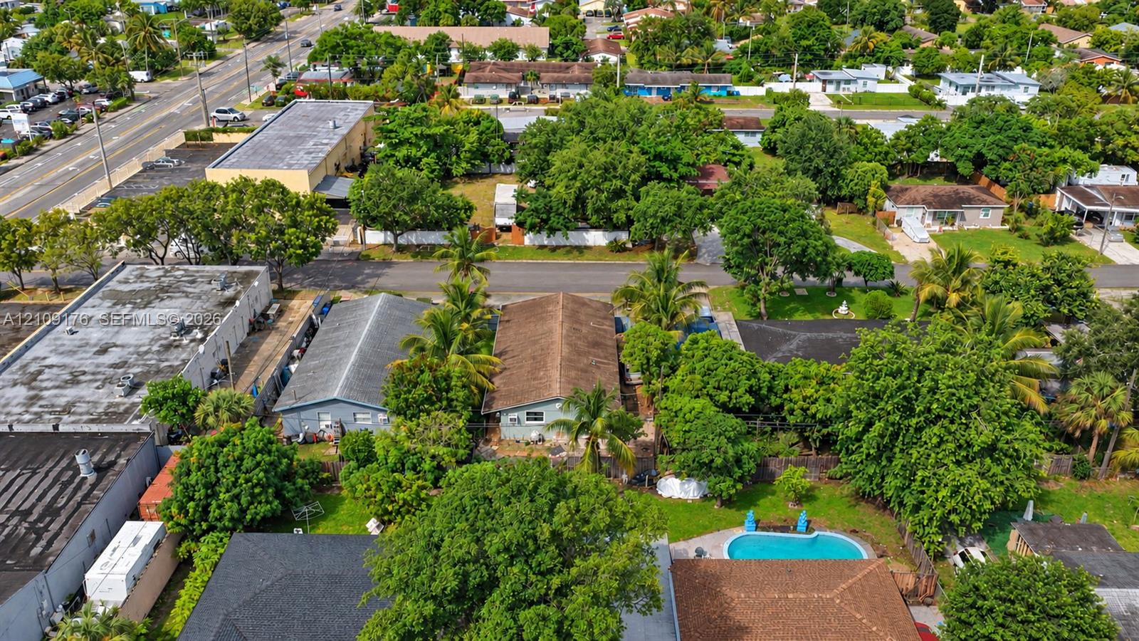 Aerial perspective featuring a detached residential structure, mature landscaping, and an inground swimming pool situated within a fenced perimeter
