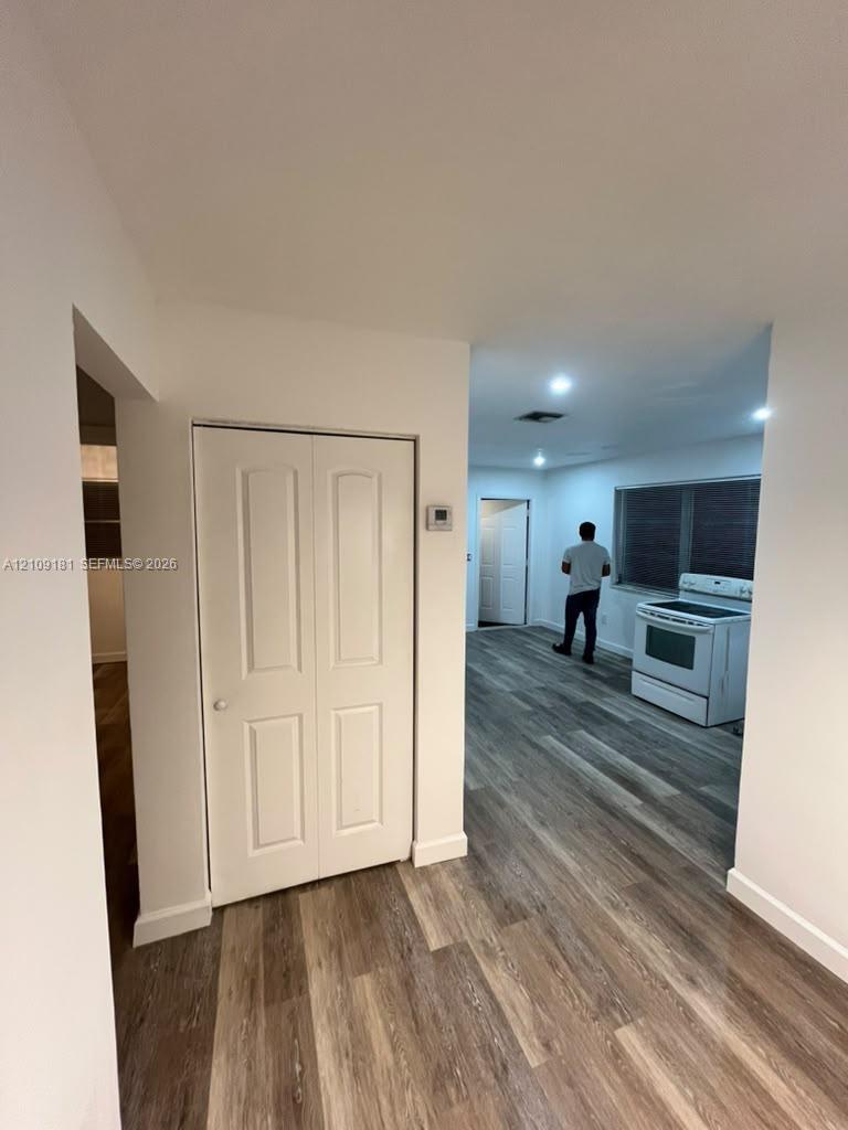 Wood-finish flooring throughout, white bi-fold closet doors, recessed ceiling lighting, and a freestanding white range