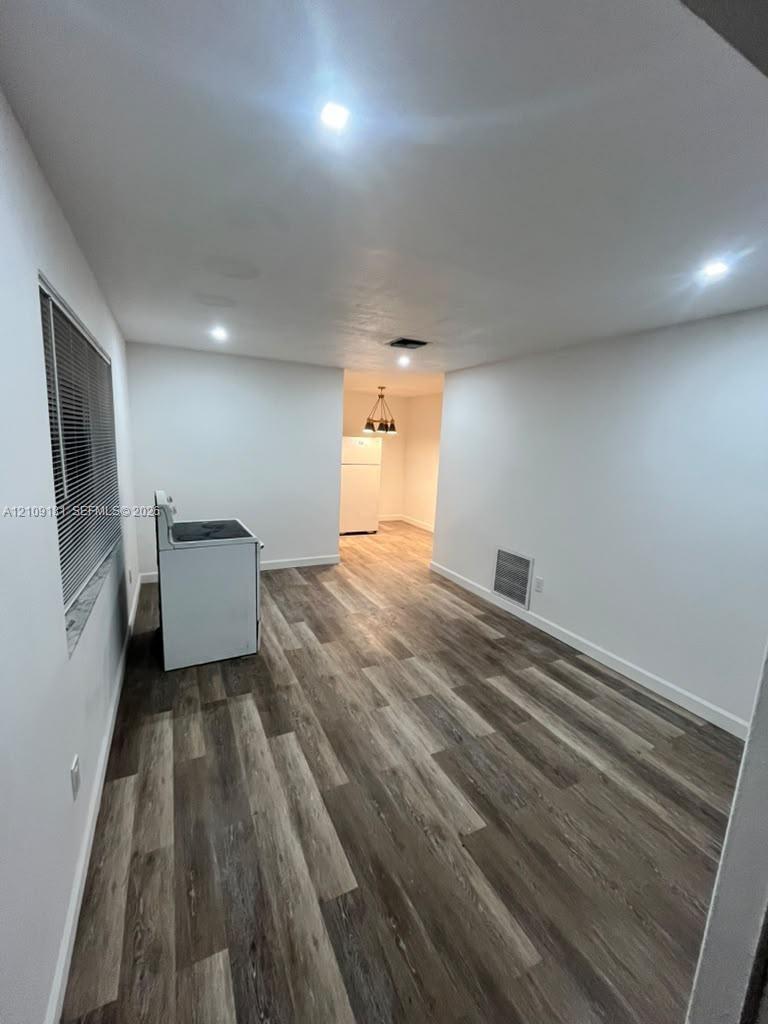 Wood-finish flooring, recessed lighting, and white walls throughout the interior
