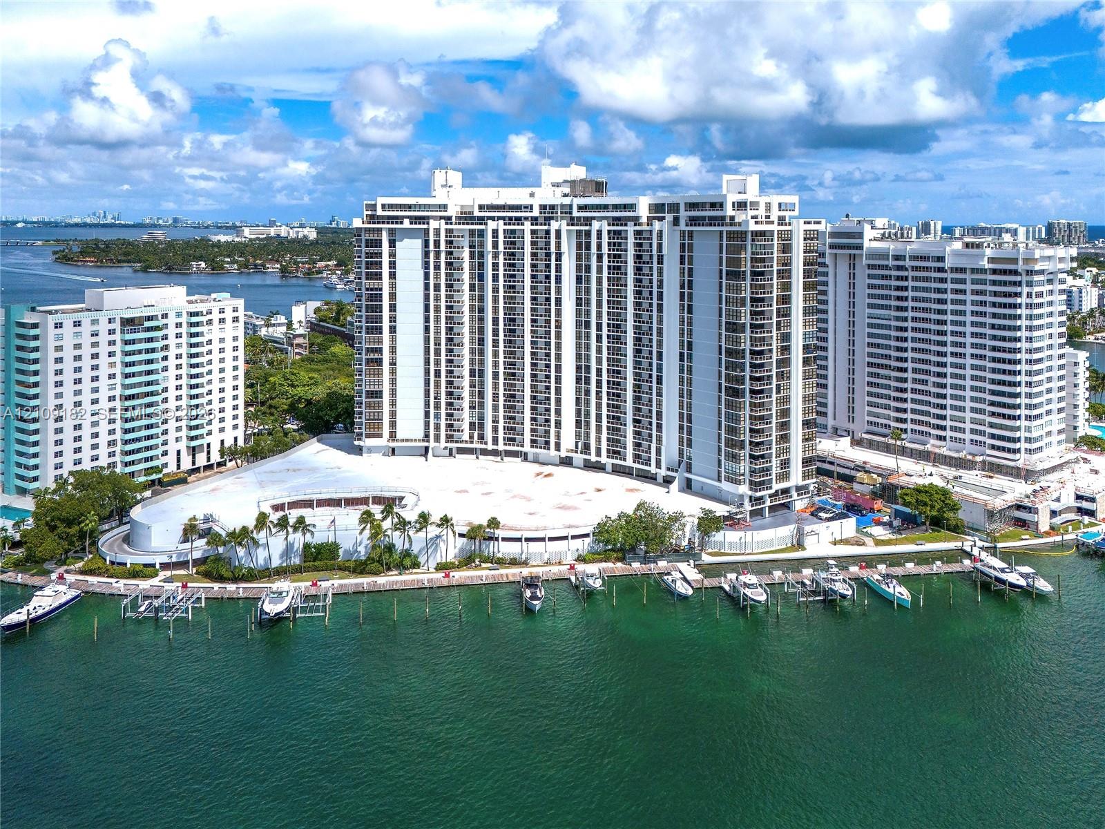 High-rise building featuring private boat slips, concrete docking structures, and perimeter palm tree landscaping