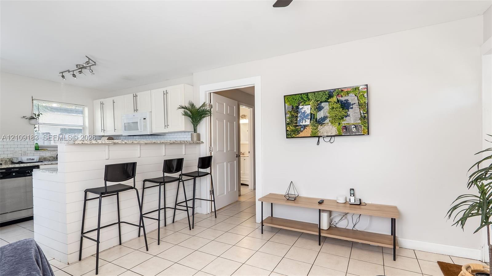 Kitchen featuring white cabinetry, stone-finish countertops, subway tile backsplash, and a breakfast bar with white shiplap detailing, complemented by tile flooring