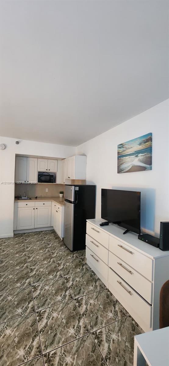 Kitchen area featuring white cabinetry, a built-in microwave, and stone-patterned tile flooring