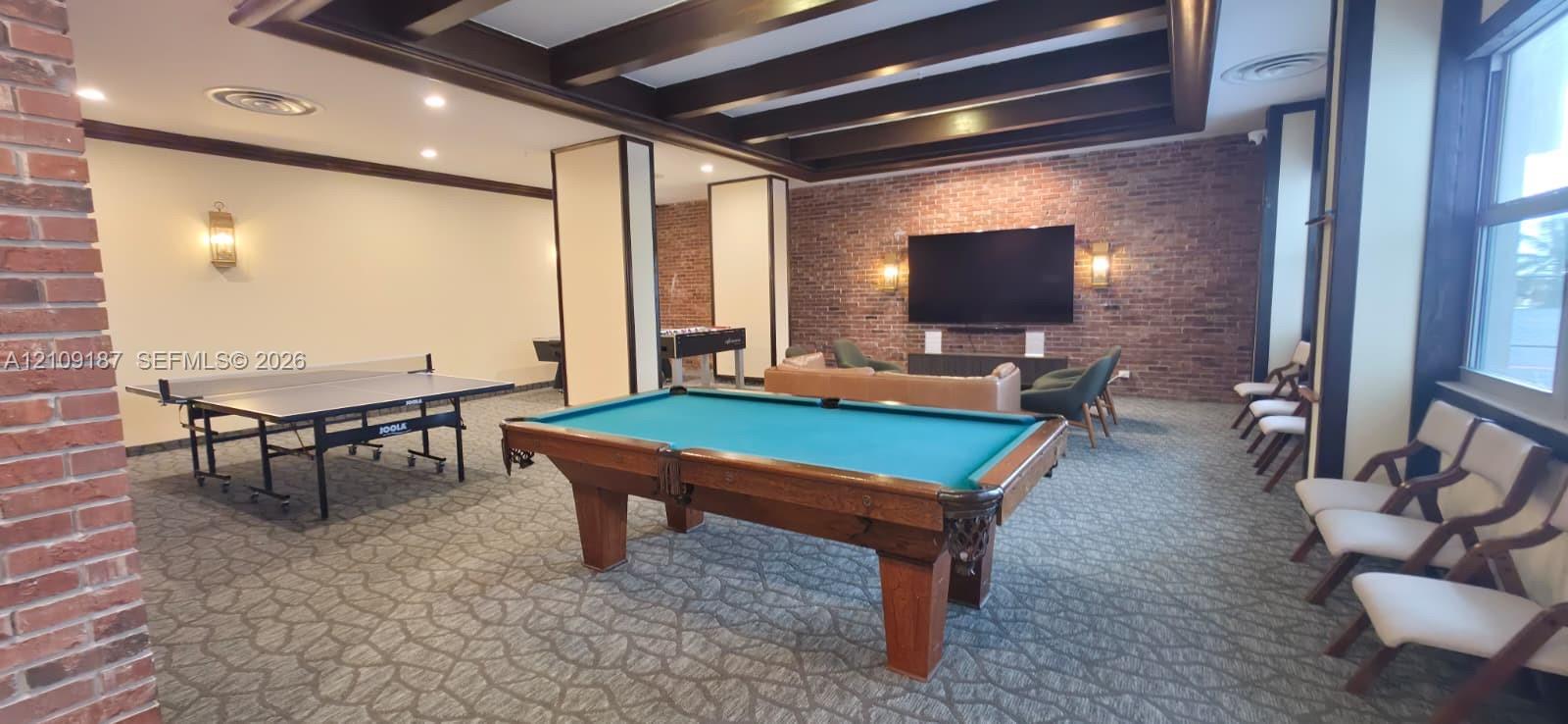 Common area featuring exposed brick walls, exposed wooden ceiling beams, recessed lighting, and large windows
