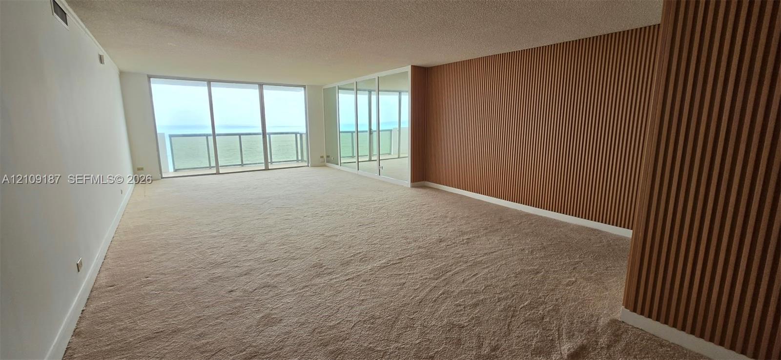 Spacious dinning-living room featuring floor-to-ceiling mirrored panels and wood-finish wall paneling. Spacious dinning-living room featuring floor-to-ceiling mirrored panels and wood-finish wall paneling.