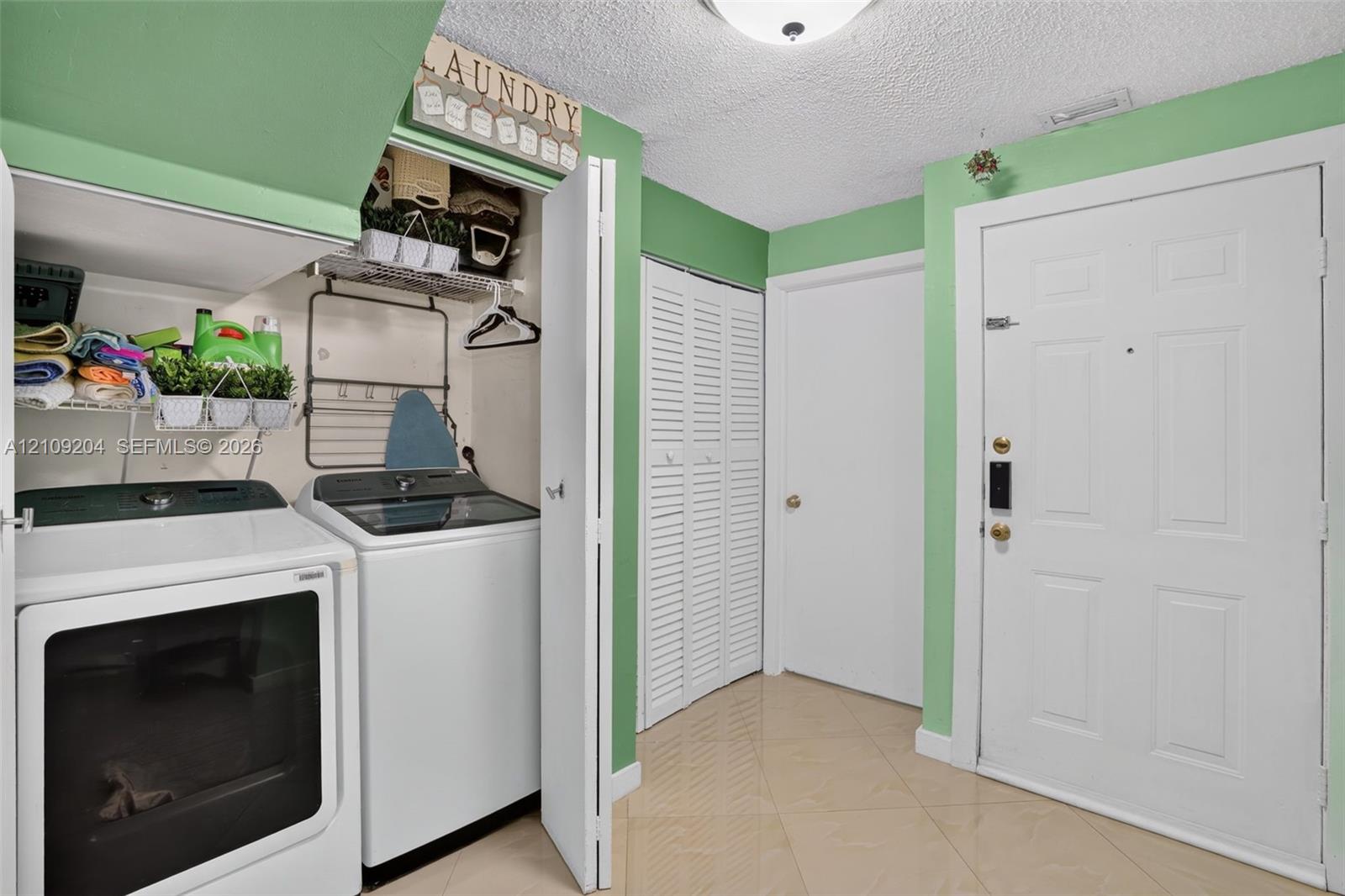 Utility area featuring built-in wire shelving, louvered closet doors, tiled flooring, and a six-panel exterior entry door Utility area featuring built-in wire shelving, louvered closet doors, tiled flooring, and a six-panel exterior entry door