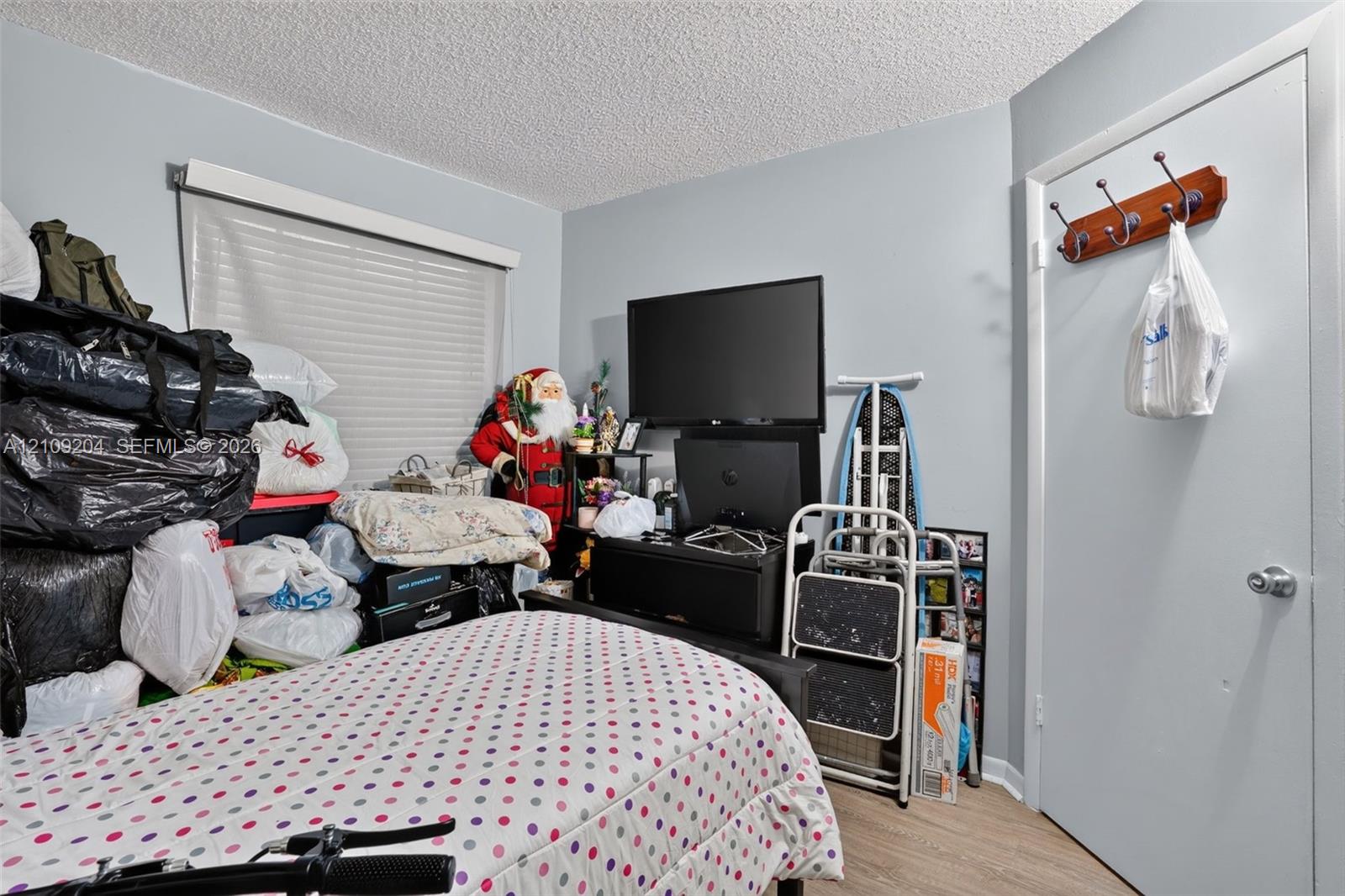 Room featuring wood-finish flooring, a neutral wall finish, and a window with fitted blinds