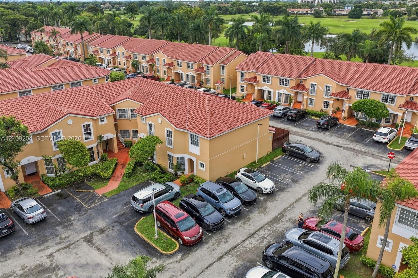 Multi-story townhome community featuring Mediterranean-style architecture, red tile roofing, stucco exterior facades, and designated surface parking Multi-story townhome community featuring Mediterranean-style architecture, red tile roofing, stucco exterior facades, and designated surface parking