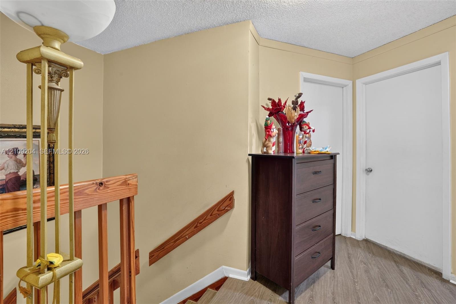 Wood-finish flooring, natural wood handrail, and white panel doors