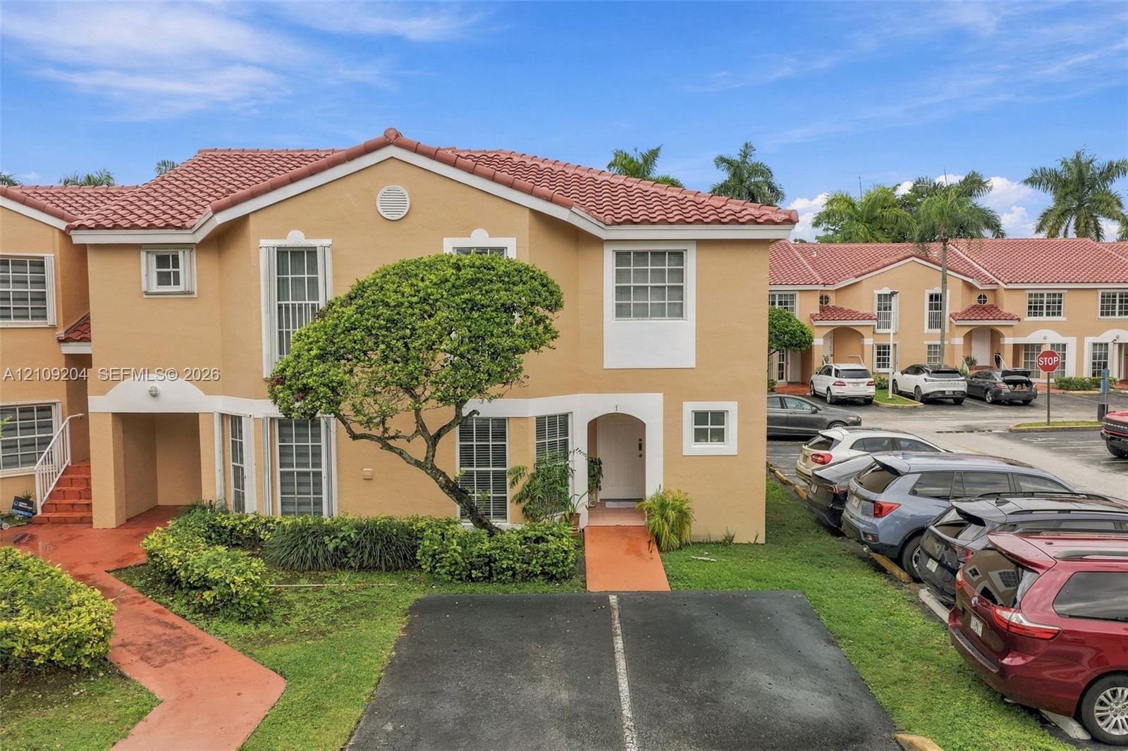 Stucco exterior featuring a mission-style clay tile roof, arched entryway, and dedicated surface parking Stucco exterior featuring a mission-style clay tile roof, arched entryway, and dedicated surface parking