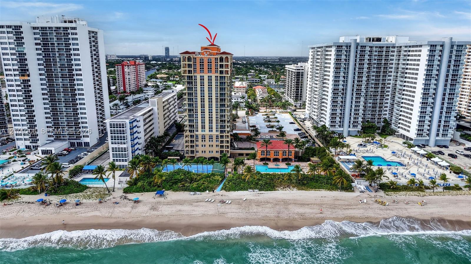 High-rise residential tower featuring a tile roof, private swimming pool, tennis court, and direct beach access