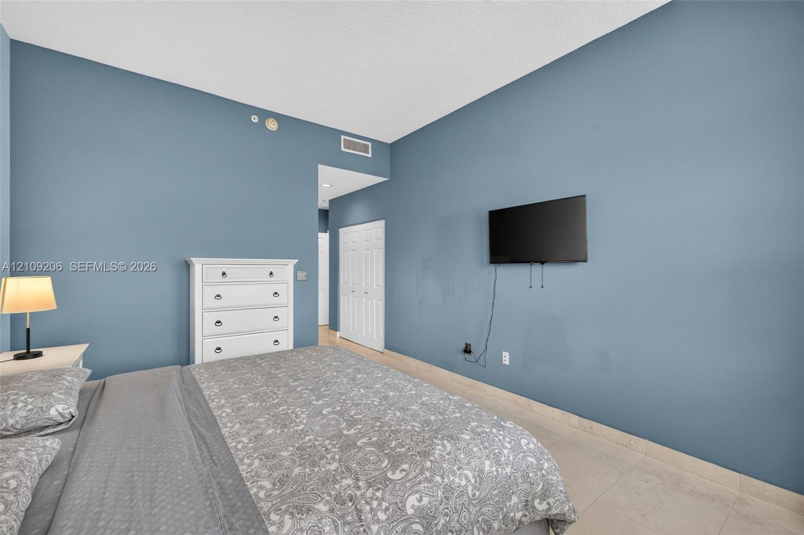 Room featuring blue painted walls, neutral stone-finish flooring, and white bifold closet doors