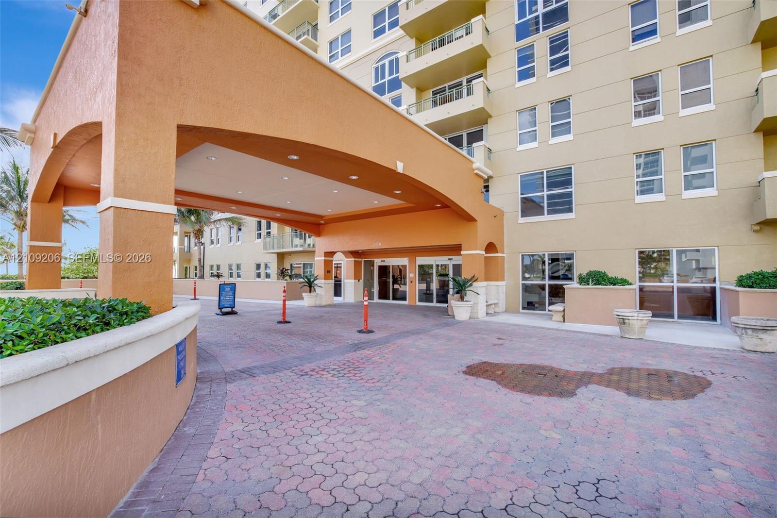 Covered porte-cochre entry featuring arched architectural detailing, recessed lighting, and a paved brick driveway