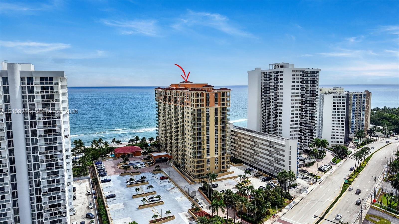 High-rise building featuring a terracotta-tiled roof, glass-railed balconies, and direct proximity to the shoreline