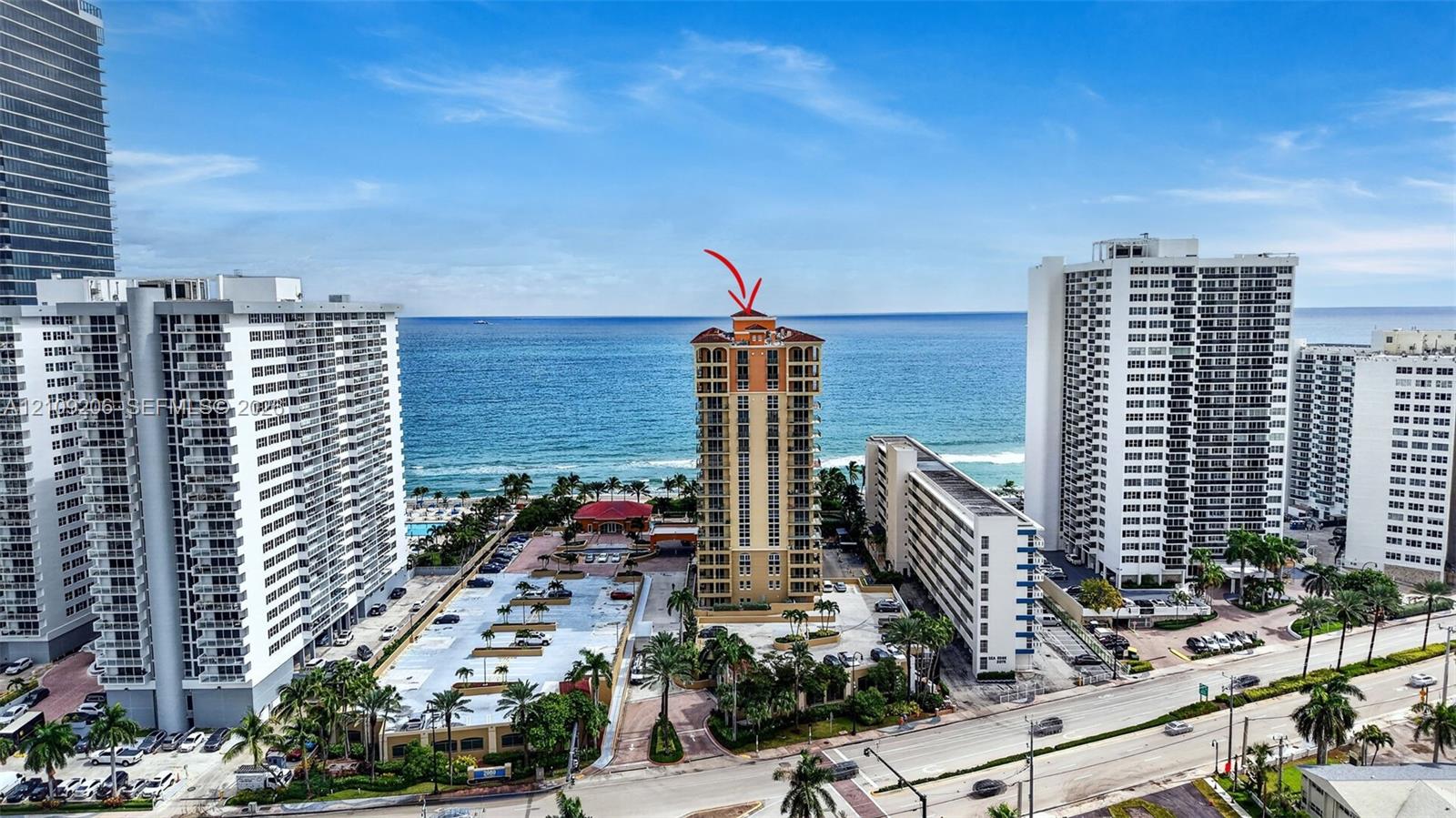 High-rise residential structure featuring multi-level balconies, an arched roofline, and direct oceanfront positioning