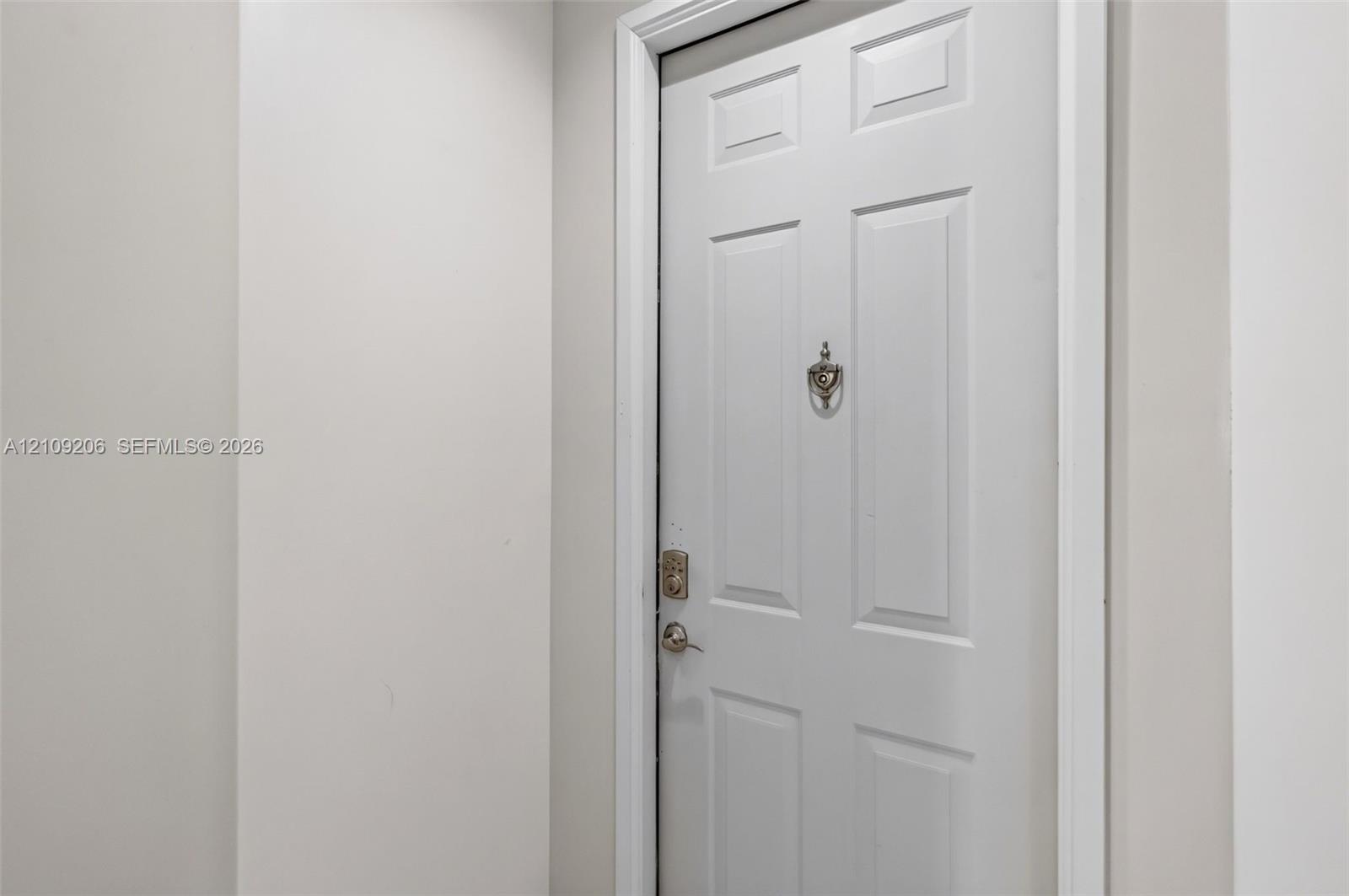 Six-panel interior door featuring a metallic knocker, deadbolt lock, and matching lever handle