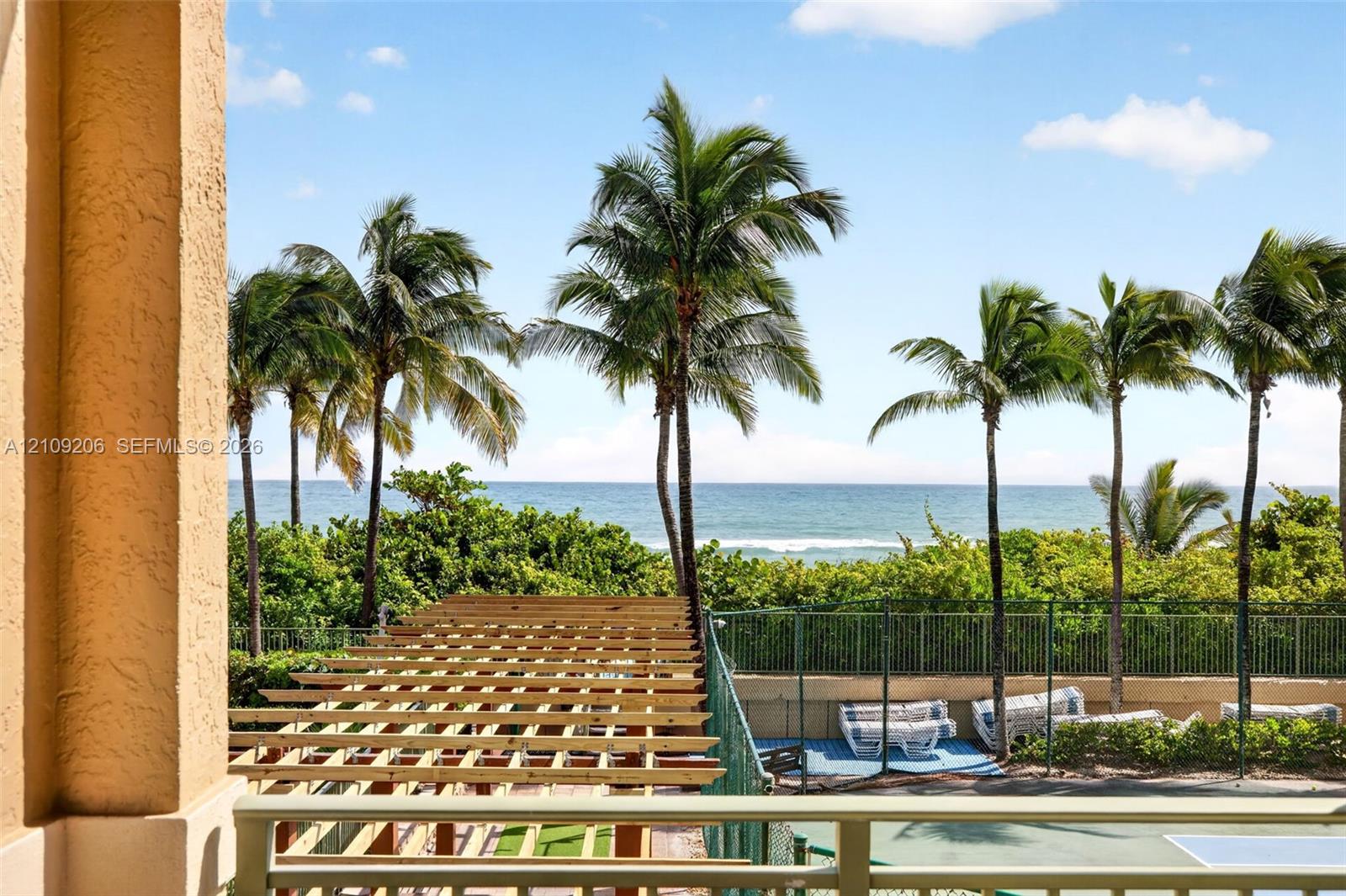 Outdoor terrace featuring a natural wood pergola, metal railing, and ocean backdrop