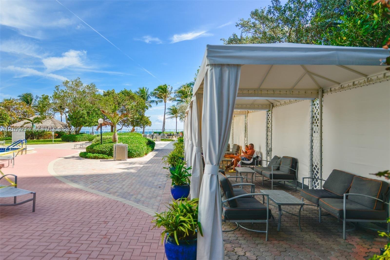 Outdoor patio featuring brick paver hardscaping, a large permanent fabric canopy structure, and mature landscaping