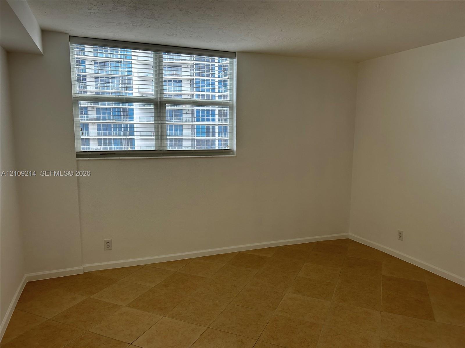 Room featuring large-format diagonal tile flooring and a multi-pane window with horizontal blinds
