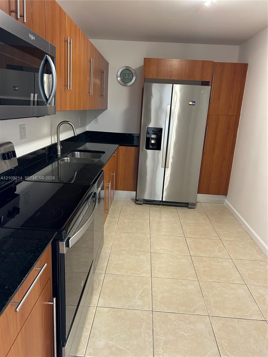 Kitchen featuring granite countertops, stainless steel appliances and large-format tile flooring