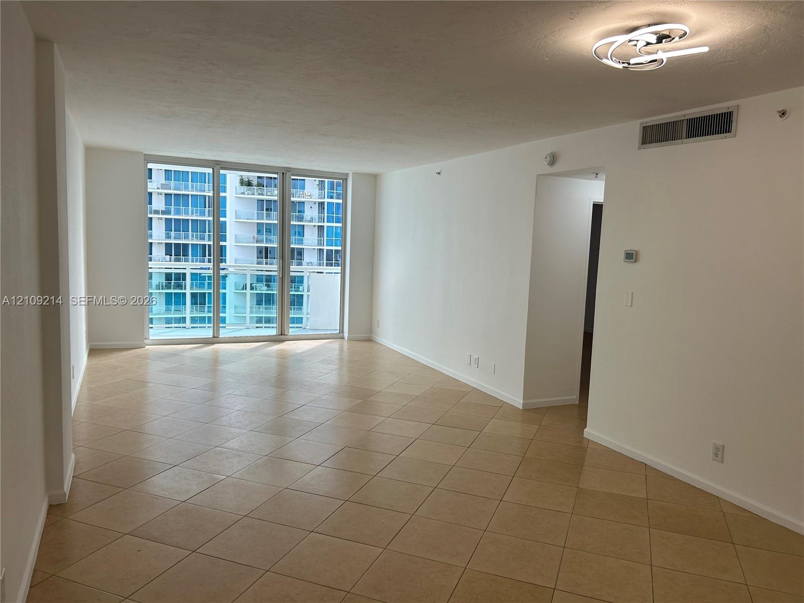 Open-concept interior featuring large-format ceramic tile flooring, floor-to-ceiling glass panel windows