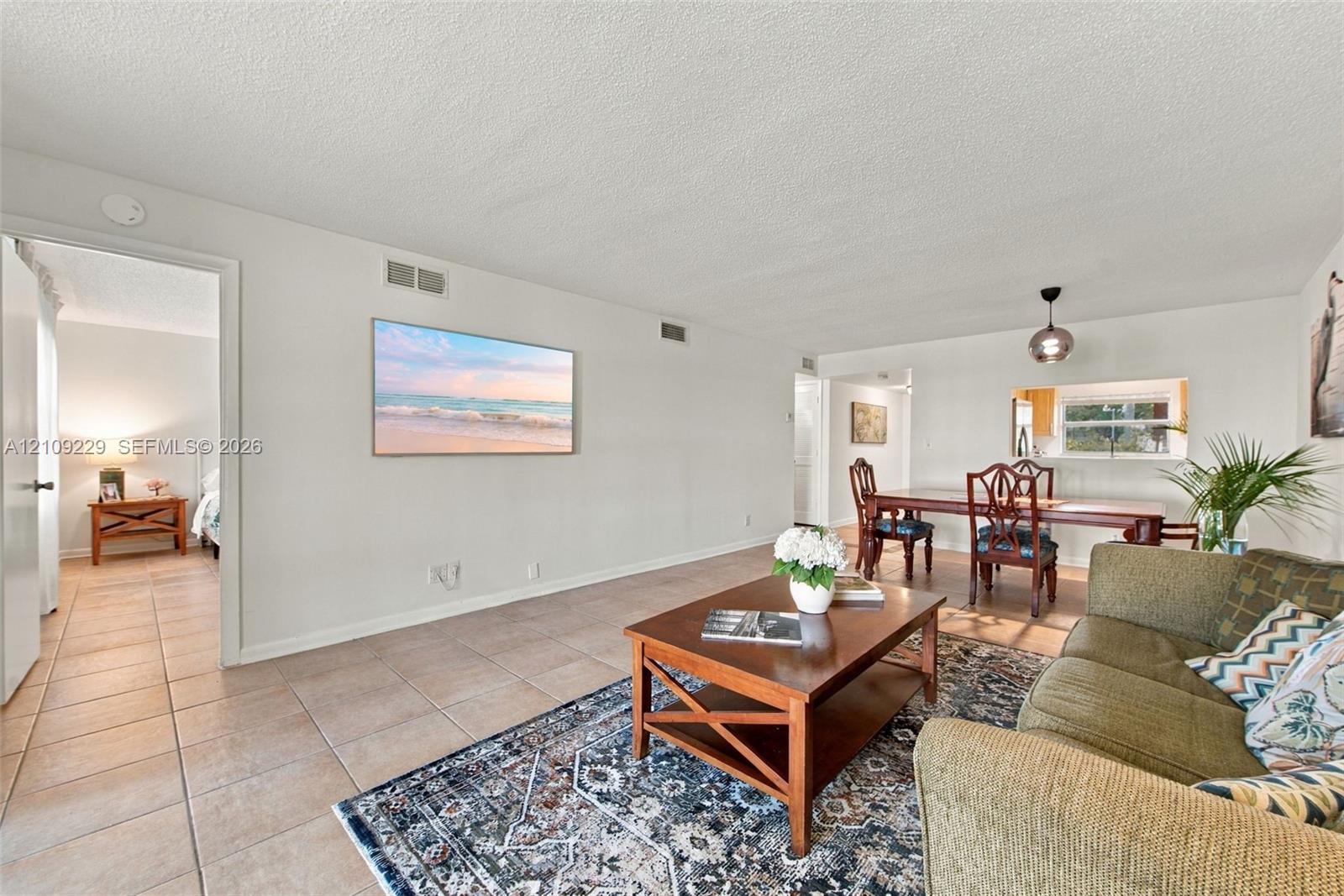 Spacious open-concept living area featuring tile flooring, recessed lighting, and large windows