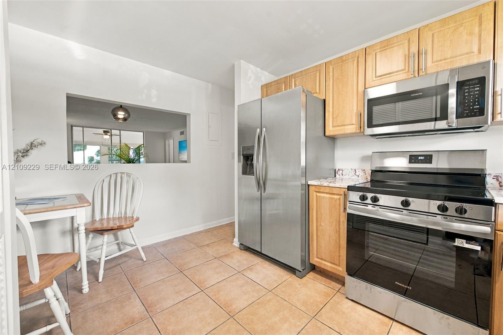 Kitchen featuring light wood cabinetry, stainless steel appliances, and tile flooring Kitchen featuring light wood cabinetry, stainless steel appliances, and tile flooring