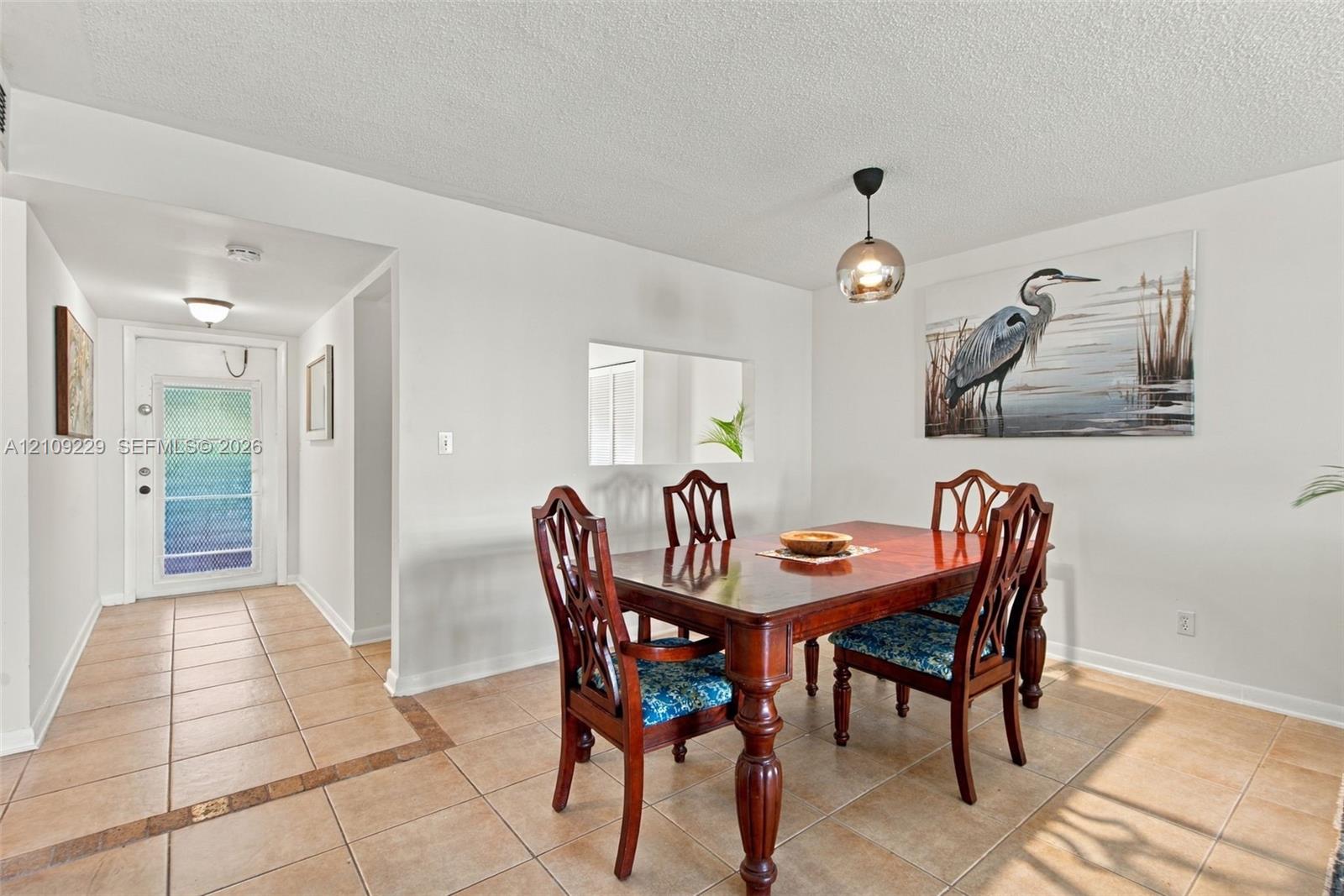 Ceramic tile flooring, decorative glass-paneled entry door, recessed ceiling lighting, and suspended globe pendant fixture