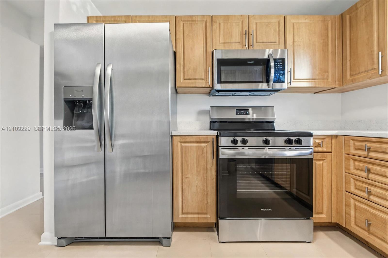Kitchen featuring wood cabinetry, stainless steel side-by-side refrigerator, stainless steel microwave, and stainless steel slide-in range Kitchen featuring wood cabinetry, stainless steel side-by-side refrigerator, stainless steel microwave, and stainless steel slide-in range