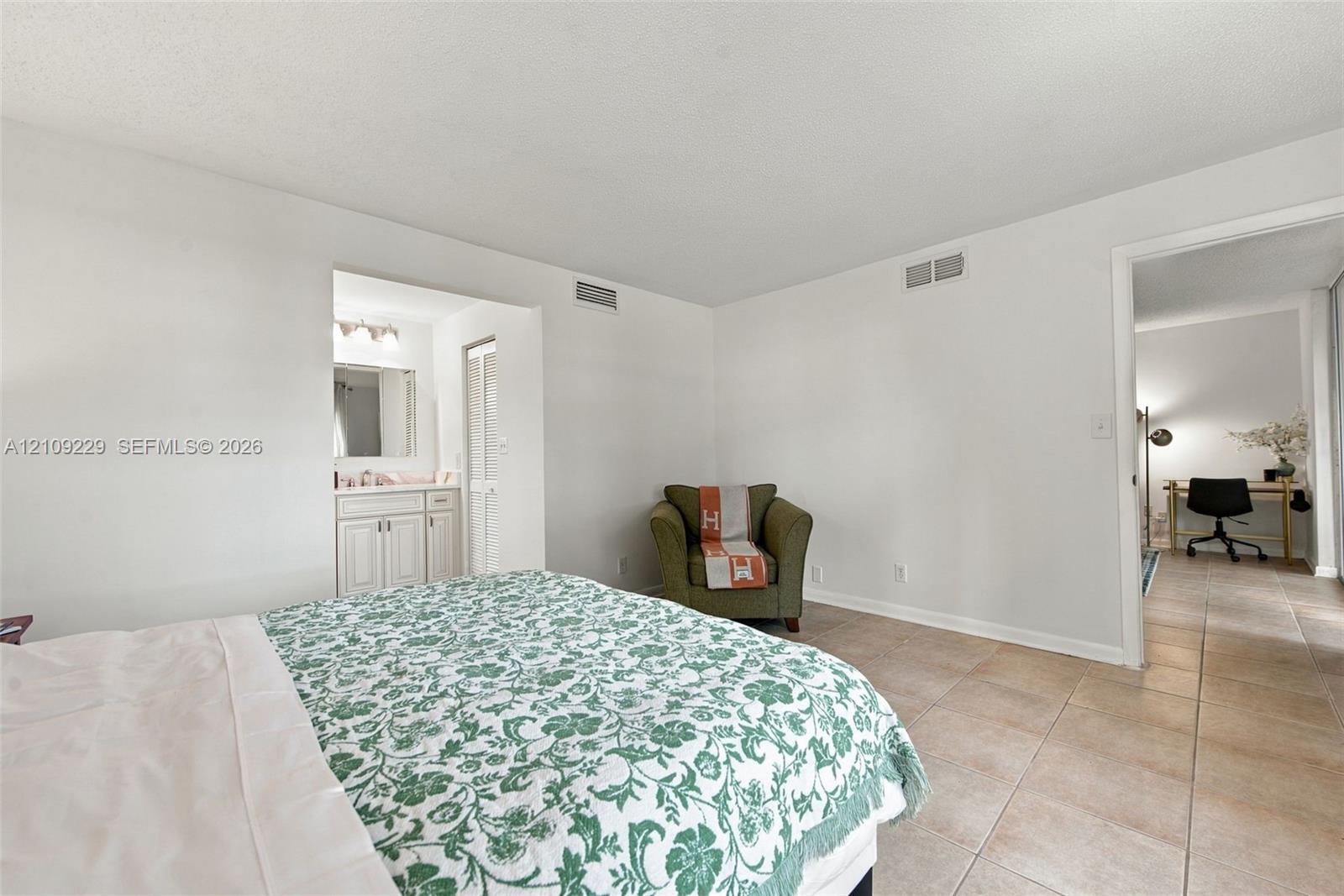 Tile flooring, neutral wall color, and built-in vanity cabinet with mirror and lighting fixture