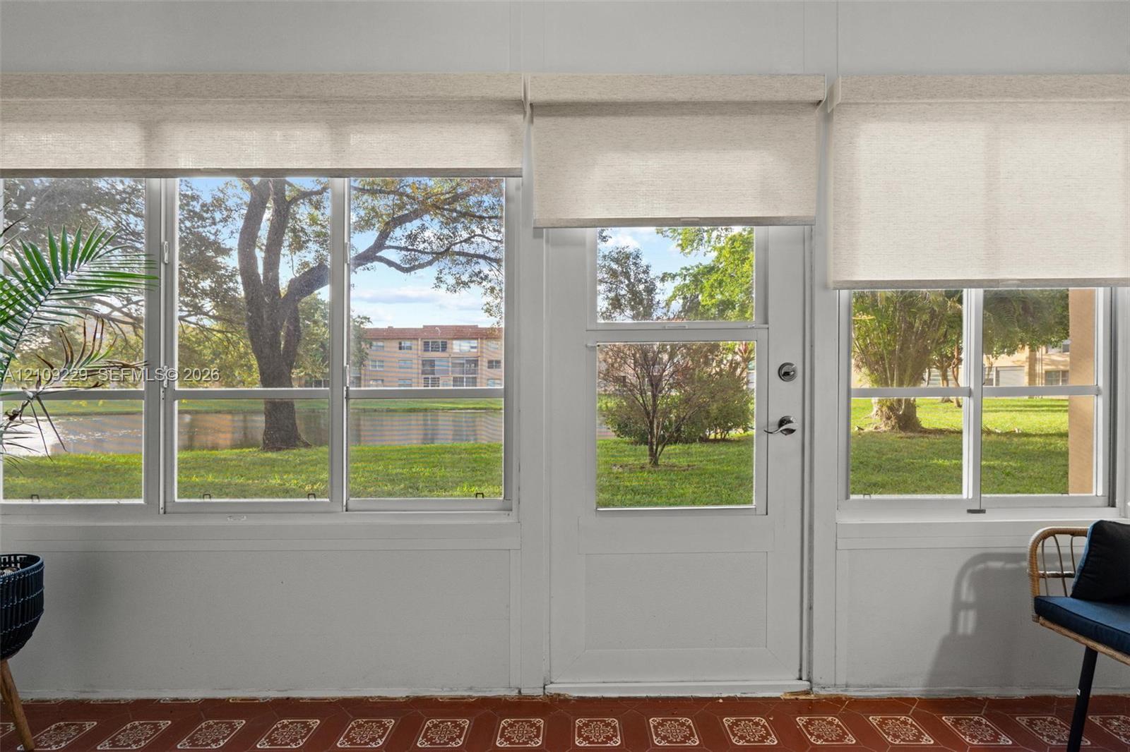 Large multi-pane windows, glass-panel entry door, and patterned tile flooring