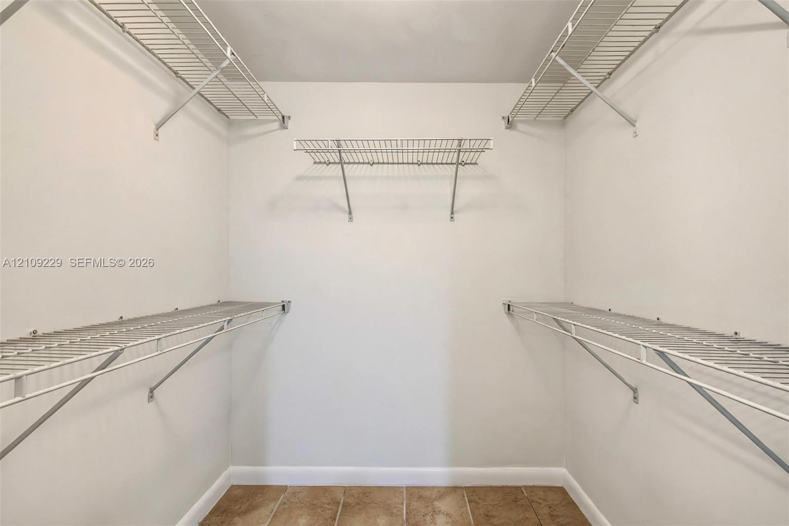 Walk-in closet featuring multi-level white wire shelving and tile flooring