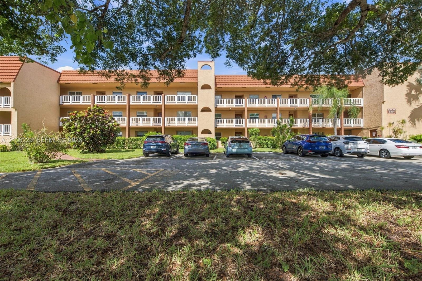 Three-story building exterior featuring a tile roof, stucco facade, and multiple levels of private balconies with white railings Three-story building exterior featuring a tile roof, stucco facade, and multiple levels of private balconies with white railings