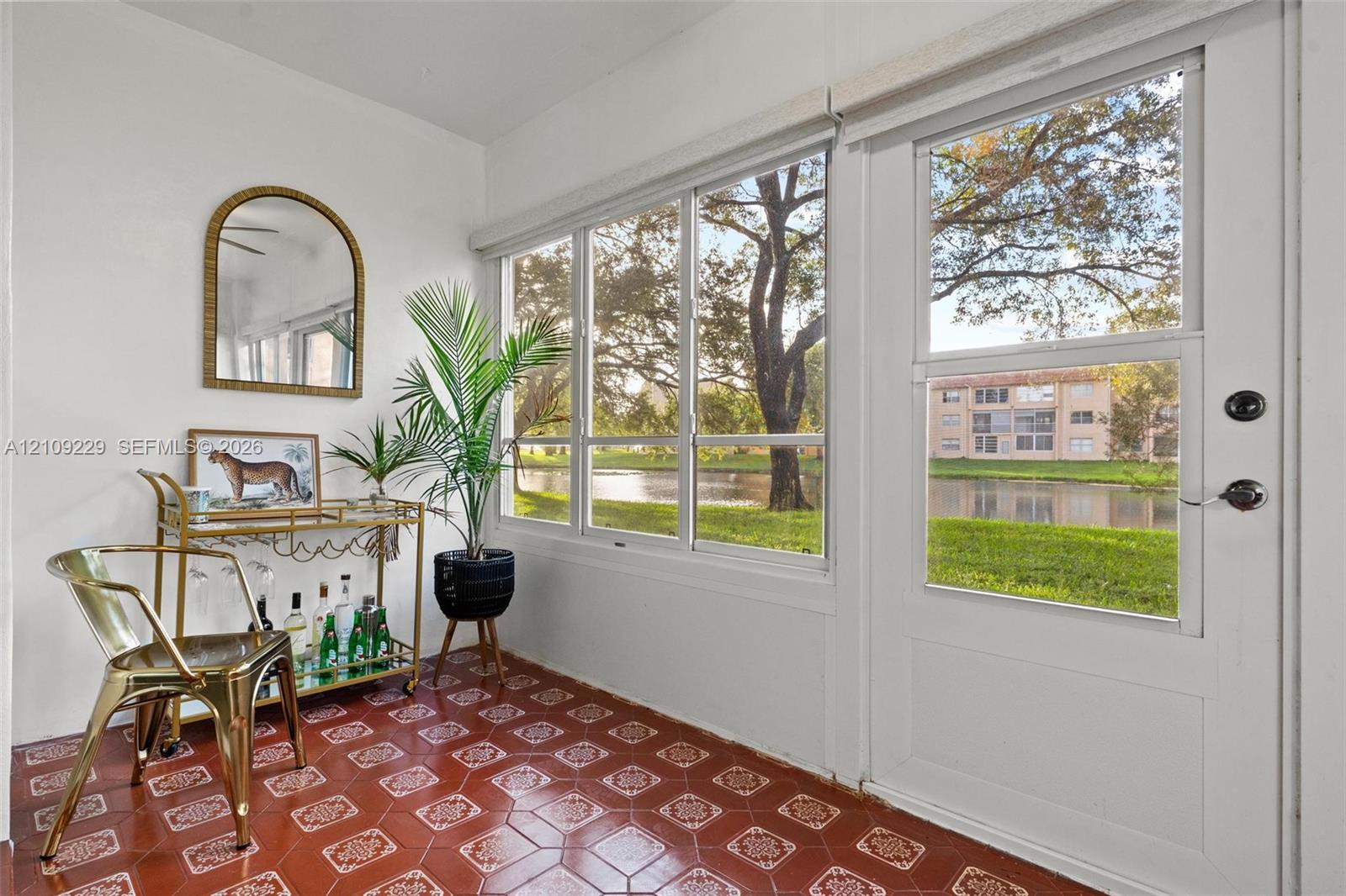 Sunroom featuring patterned terracotta-style tile flooring, floor-to-ceiling windows, and a glass-paneled exterior door