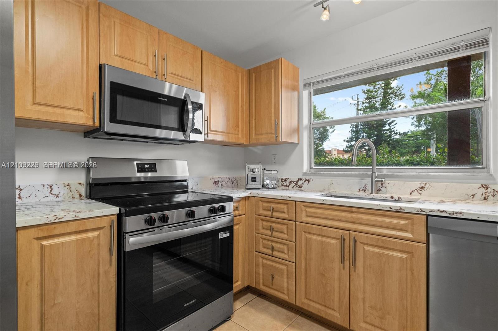 Kitchen featuring light-finish cabinetry, stone-patterned countertops, stainless steel appliances, and a polished metal faucet Kitchen featuring light-finish cabinetry, stone-patterned countertops, stainless steel appliances, and a polished metal faucet