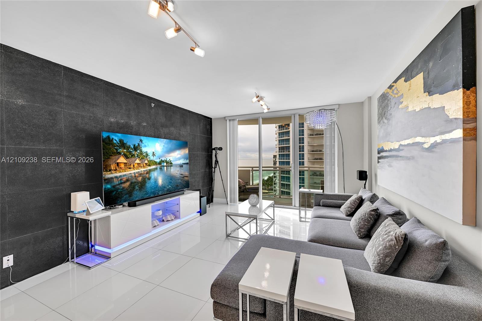 Large-format tile accent wall, polished tile flooring, and floor-to-ceiling glass door